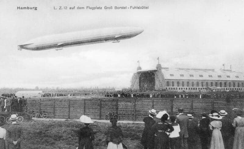 Kapal udara Zeppelin LZ 12 yang sedang melintas di atas lapangan terbang Groß Borstel-Fuhlsbüttel di Hamburg, Jerman. Area lapangan terbang tersebut merupakan cikal bakal dari Bandar Udara Hamburg.