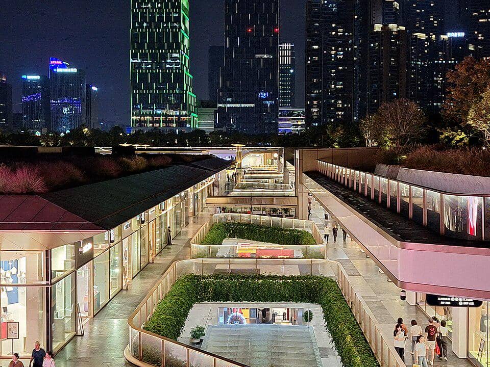 Pemandangan malam SKP Chengdu Mall dengan pencahayaan modern, gedung tinggi di latar belakang, dan pengunjung berjalan di area terbuka.