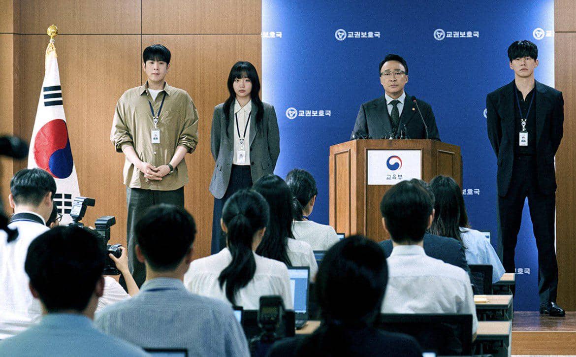Empat orang berdiri di depan podium konferensi pers dengan latar bendera Korea Selatan dan logo lembaga pemerintah, dihadiri para jurnalis.