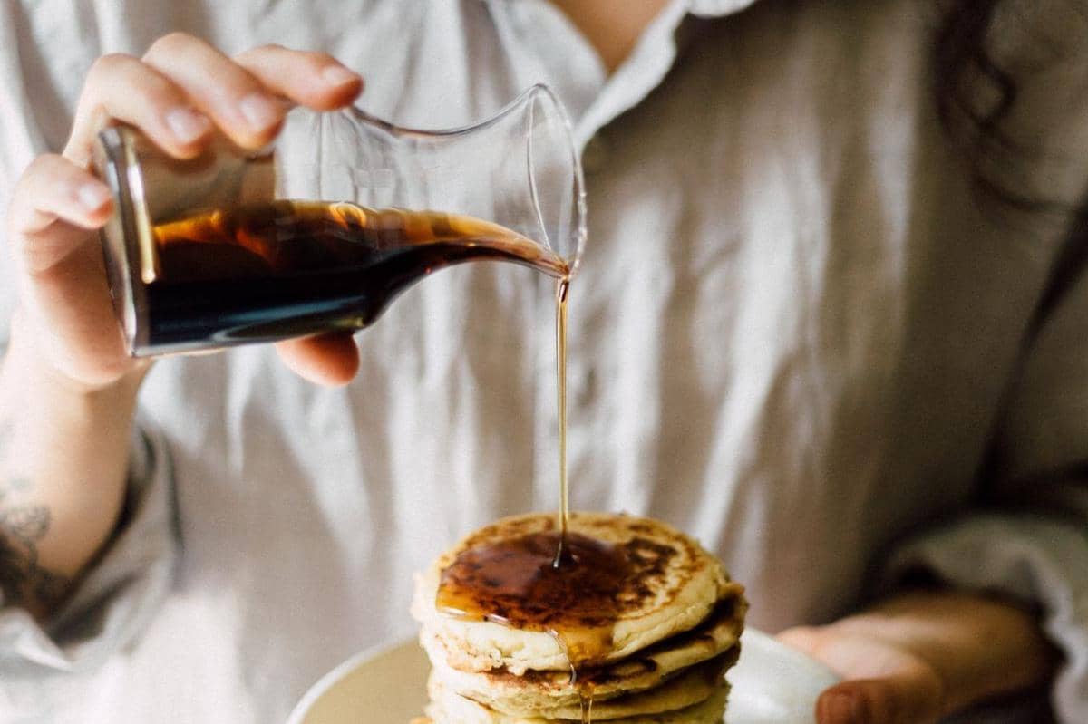 ilustrasi orang menuangkan sirup di atas pancake