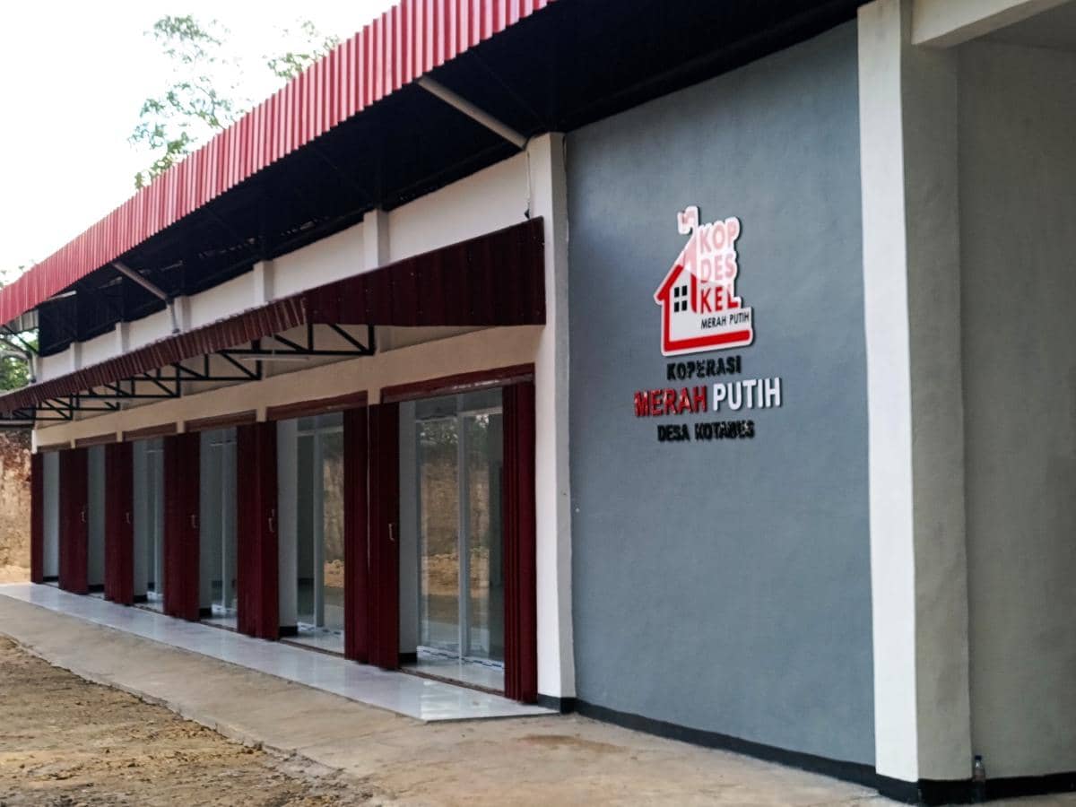 Bangunan Koperasi Merah Putih di Desa Kotabes, Kupang, Nusa Tenggara Timur, dengan deretan pintu kaca dan dinding abu-abu merah.