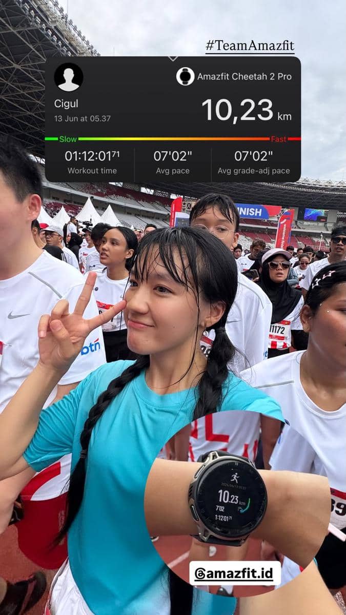 Seorang peserta marathon mengenakan kaus biru berpose dengan tanda damai di Stadion Utama Gelora Bung Karno setelah lari 10,23 km.