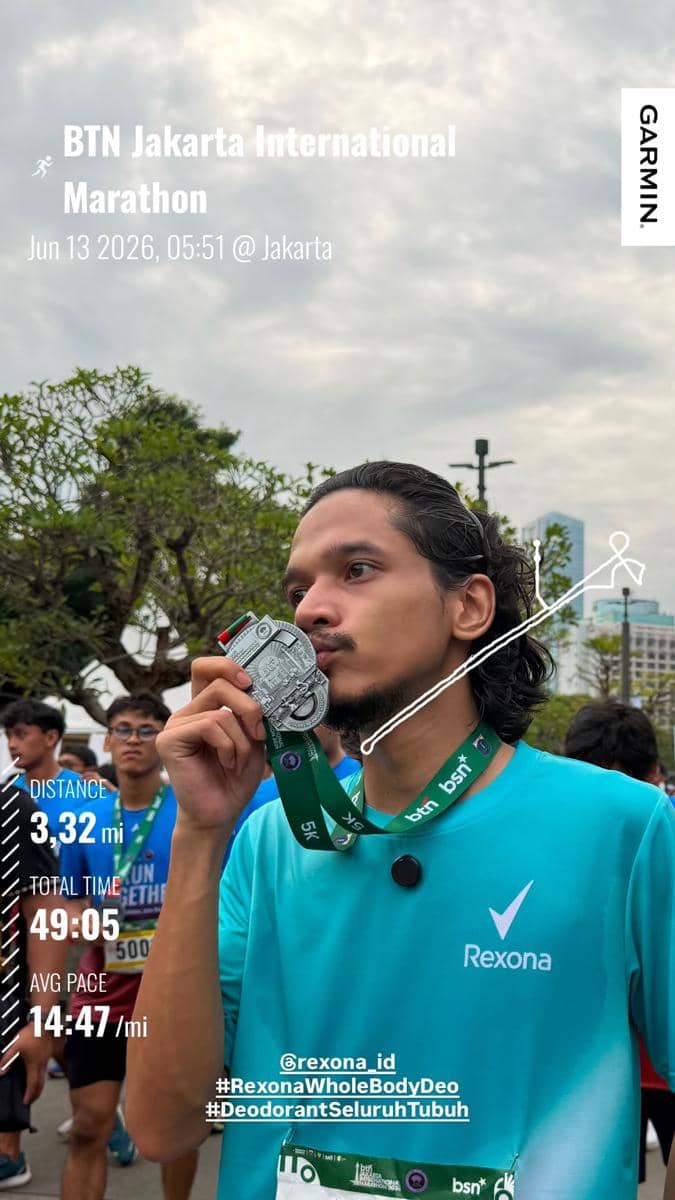 Seorang pelari mengenakan kaus biru mencium medali setelah menyelesaikan BTN Jakarta International Marathon 2026 di Jakarta.