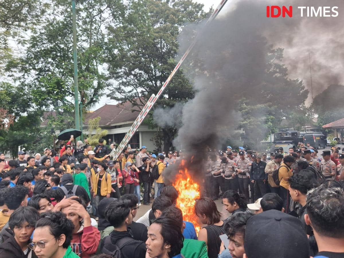 Ratusan mahasiswa di Purwokerto berkumpul di halaman pendopo Si Panji sambil membakar ban dengan asap hitam tebal di tengah pengawasan polisi.