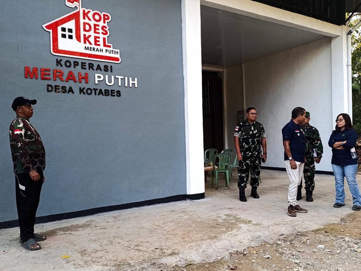 Beberapa orang berdiri di depan gedung Koperasi Merah Putih Desa Kotabes, Kupang, NTT, menunggu pasokan listrik PLN.