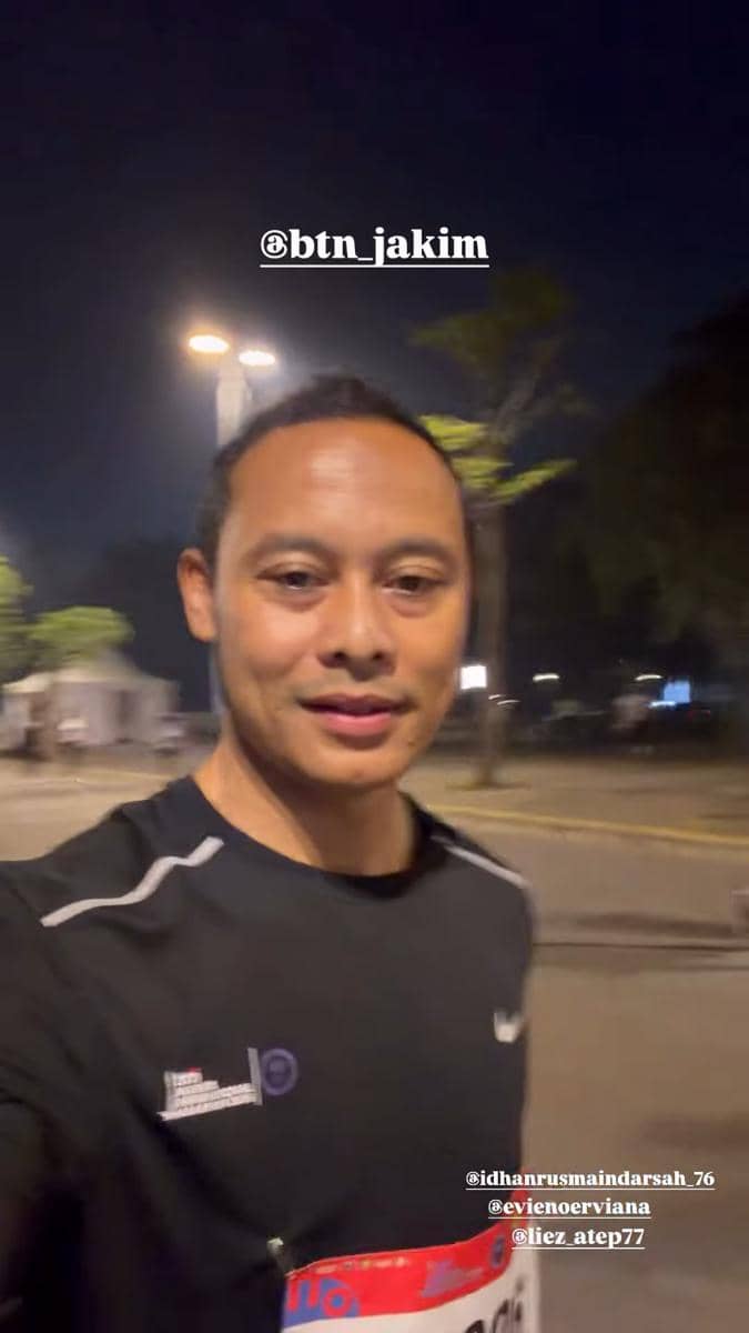 Seorang pelari mengenakan kaus hitam dengan nomor peserta mengikuti Jakarta International Marathon 2026 pada malam hari.