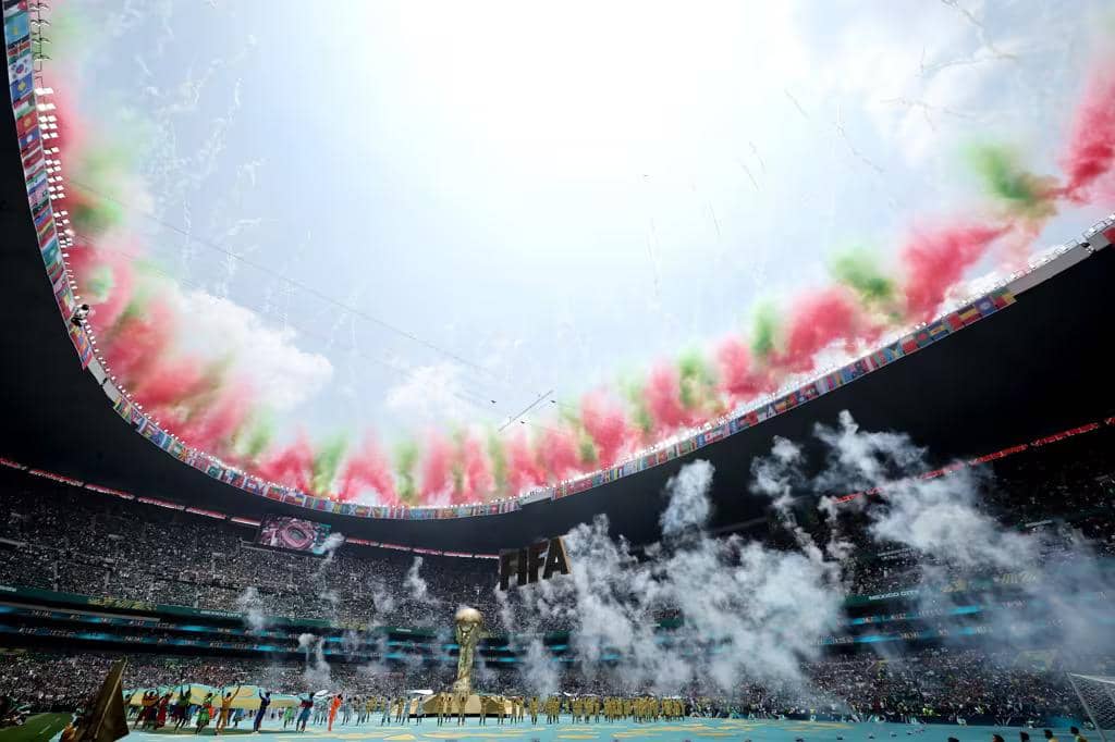 Suasana megah opening ceremony Piala Dunia 2026 di dalam Stadion Azteca dengan kembang api warna-warni dan replika trofi emas FIFA raksasa di tengah lapangan.