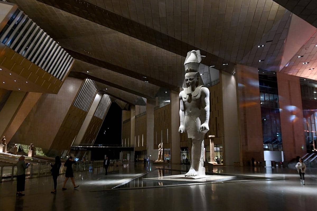 Patung kolosal Firaun Ramses II yang menjulang tinggi di dalam atrium utama Grand Egyptian Museum.