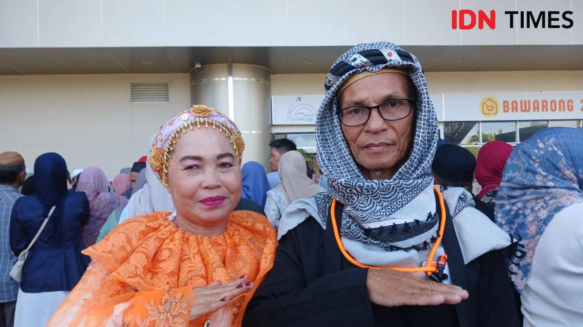 Dua jemaah haji asal Bolmong mengenakan pakaian khas Bugis berwarna cerah dan sorban hitam putih saat tiba di tanah air setelah menunaikan ibadah haji.
