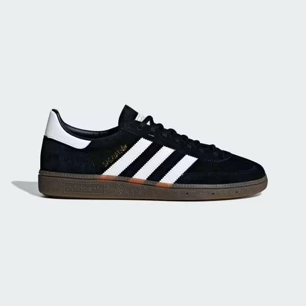 Sepatu Adidas Spezial berwarna hitam dengan tiga garis putih di sisi dan sol karet cokelat bergaya klasik.