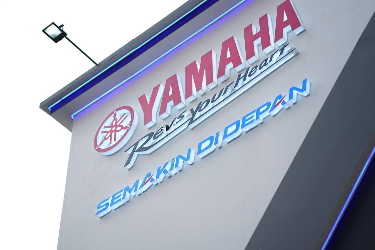 Tampak dekat logo Yamaha dengan tulisan Revs Your Heart dan Semakin di Depan di dinding booth pameran JFK 2026.