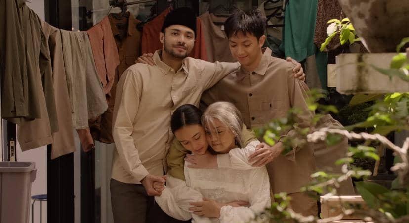 Empat orang berdiri berpelukan di halaman rumah dengan latar jemuran pakaian, menampilkan suasana hangat dan penuh kasih.