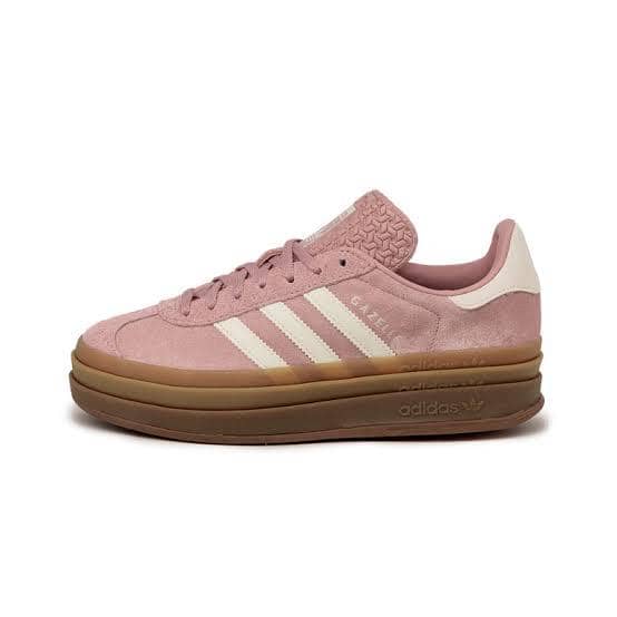 Sepatu Adidas Gazelle berwarna merah muda dengan sol tebal cokelat dan tiga garis putih khas di sisi samping.