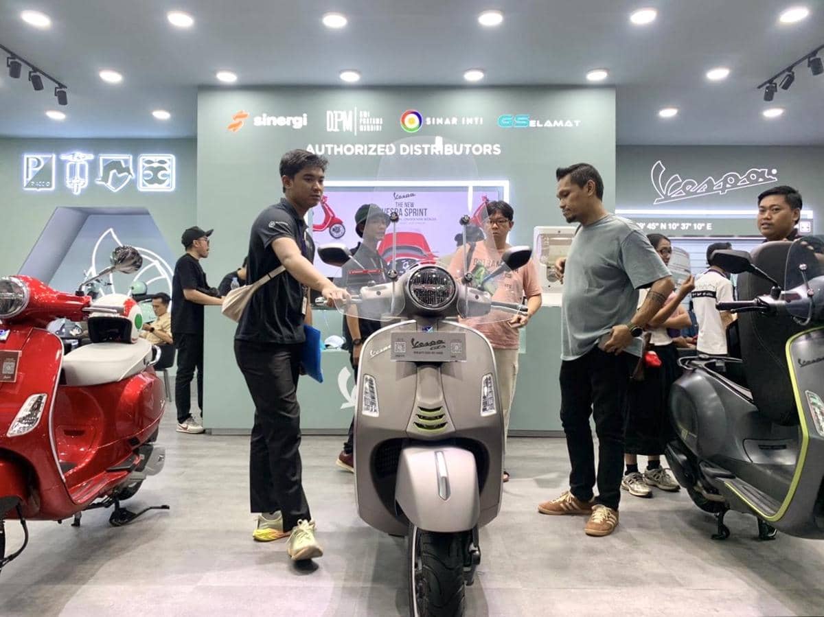 Beberapa pengunjung melihat dan berdiskusi di stan Vespa yang memamerkan berbagai model skuter pada acara JFK 2026.