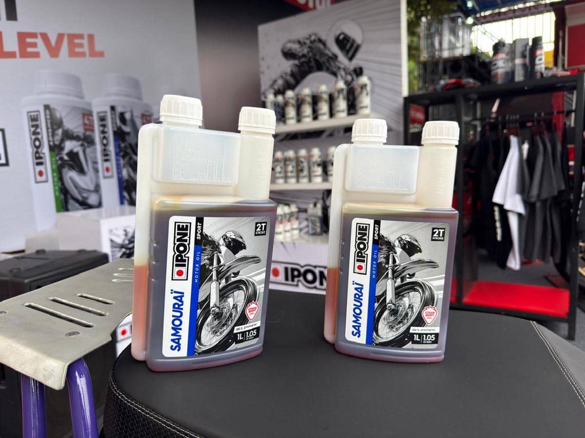 Dua botol oli motor Ipone Samouraï 2T Synthetic Ester 1 liter dipajang di atas meja dengan latar belakang stan produk Ipone.