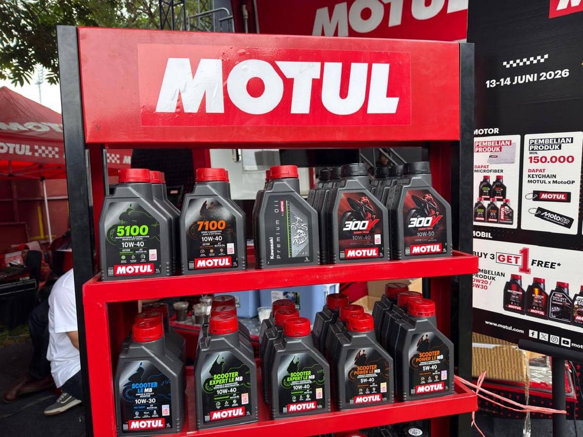 Rak produk oli motor Motul berbagai varian dengan promo beli tiga gratis satu di sebuah stan pameran otomotif.