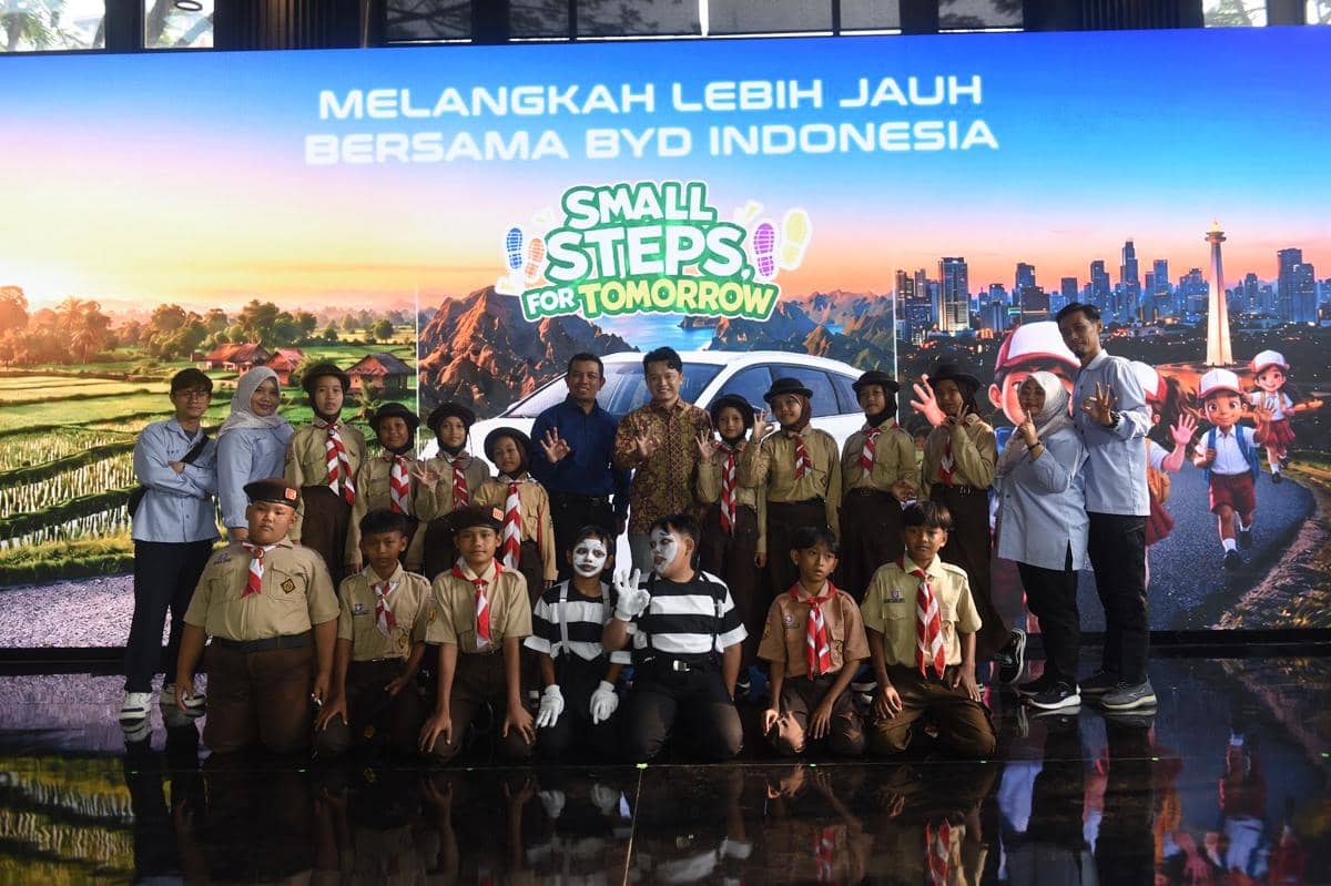 Sejumlah siswa berseragam pramuka berfoto bersama panitia di depan layar bertuliskan 'Small Steps for Tomorrow' dari BYD Indonesia.