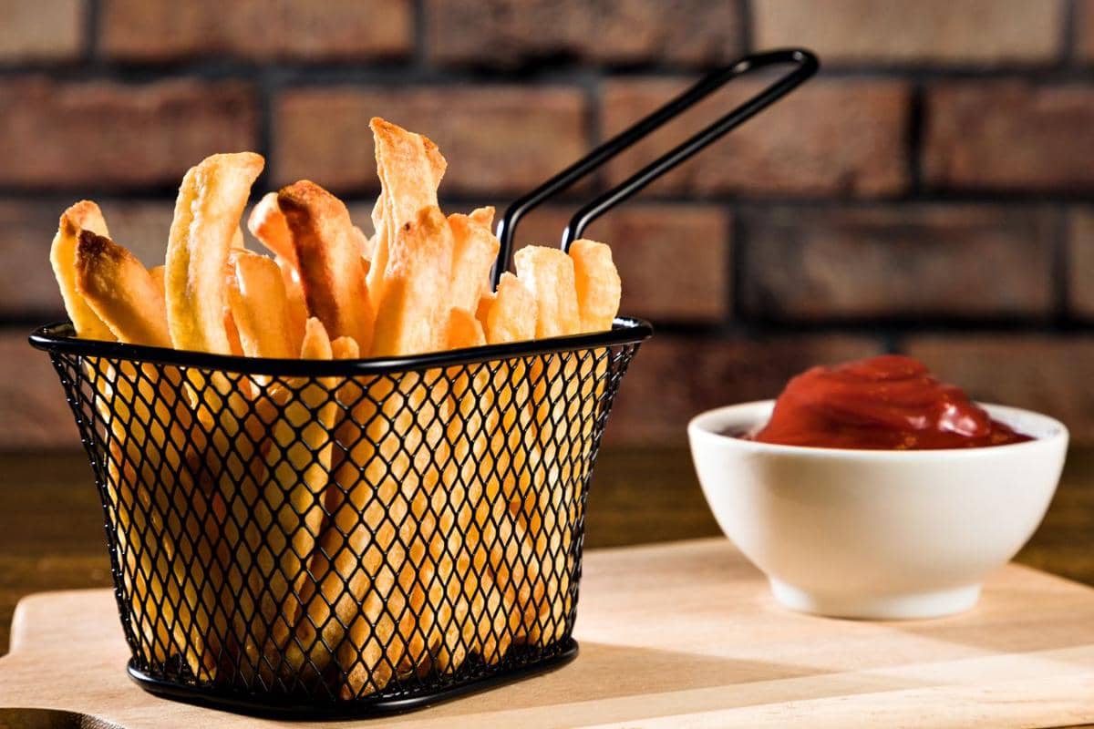 https://www.pexels.com/photo/closeup-of-a-frying-basket-with-french-fries-and-bowl-of-ketchup-against-brick-wall-13187600/