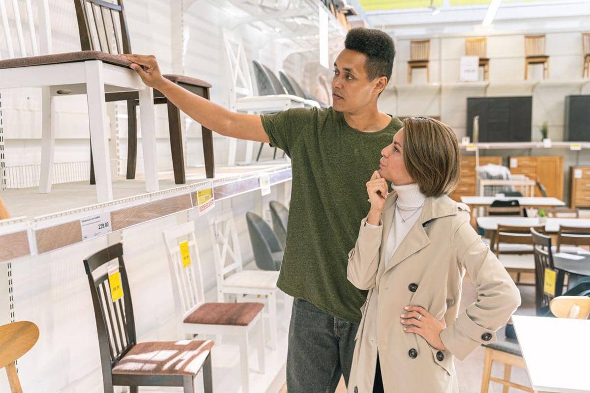ilustrasi sepasang suami istri sedang memeriksa kursi di lorong toko furnitur