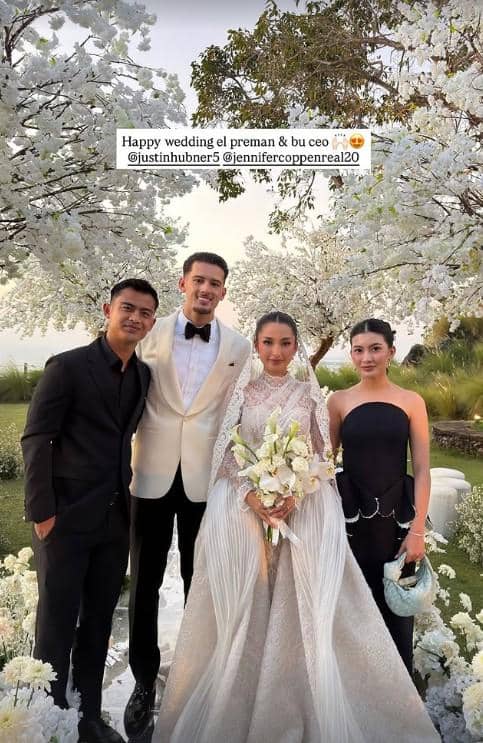 Empat orang berpose di taman dengan dekorasi bunga putih saat resepsi pernikahan, pengantin mengenakan gaun dan jas elegan.