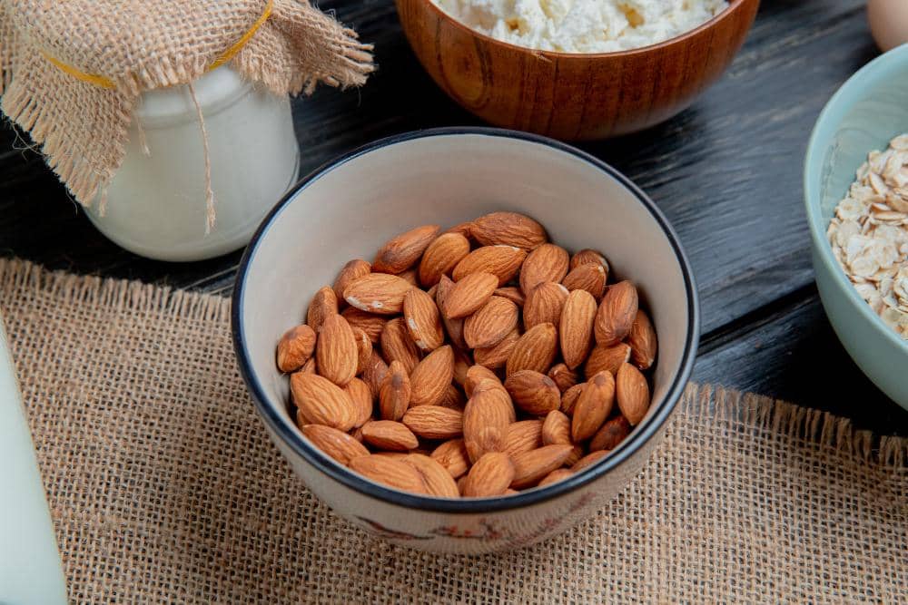 Ilustrasi kacang almond dengan cangkang cokelat dan biji berwarna krem sebagai gambaran bahan pangan bernutrisi.