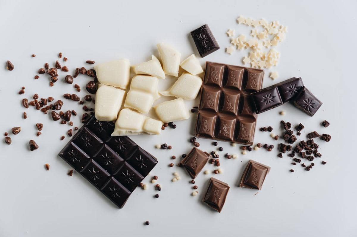 Aneka cokelat batangan, praline, dan bubuk cokelat tersusun sebagai ilustrasi berbagai jenis cokelat.
