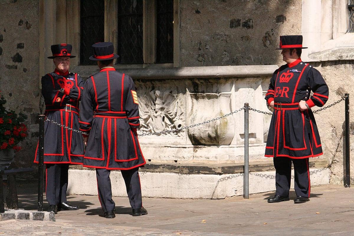 Para Yeomen Warders, yang populer dikenal sebagai "Beefeaters", sedang berdiri di luar di halaman Menara London.
