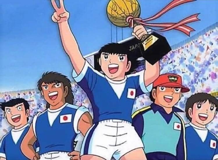 Karakter anime mengenakan seragam sepak bola Jepang merayakan kemenangan dengan mengangkat trofi emas di stadion penuh penonton.