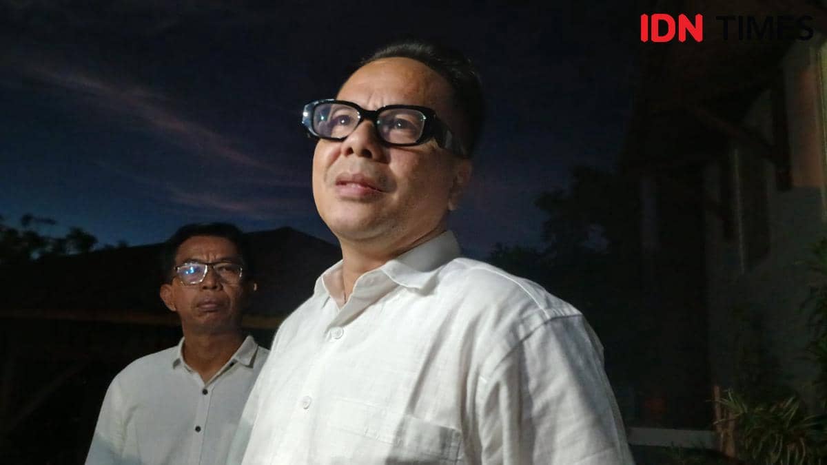 Dua pria mengenakan kemeja putih berdiri di luar ruangan pada malam hari dengan latar langit gelap di Manado, Sulawesi Utara.