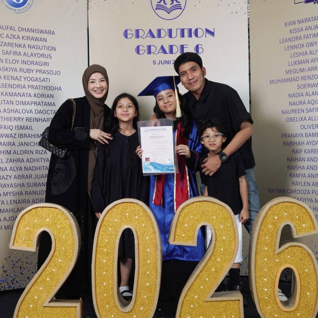 Keluarga berpose bersama anak yang mengenakan toga wisuda dan memegang ijazah di acara kelulusan tahun 2026.