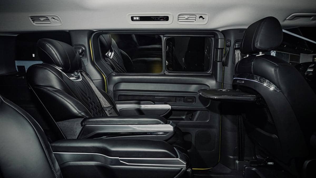 Interior mobil Volkswagen ID. Buzz dengan fitur Smartdeck, menampilkan kursi kulit hitam mewah dan meja lipat di bagian tengah.