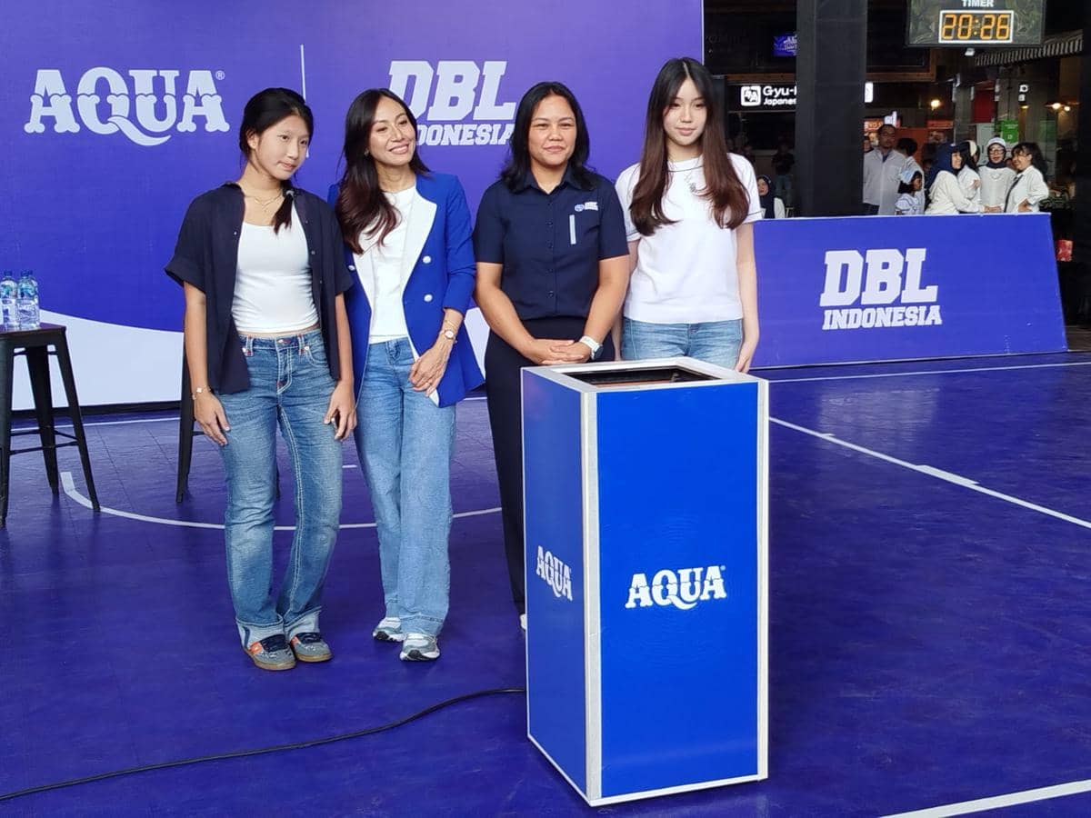 Empat perempuan berpose di lapangan basket dengan latar belakang logo Aqua dan DBL Indonesia dalam acara kolaborasi untuk generasi muda.