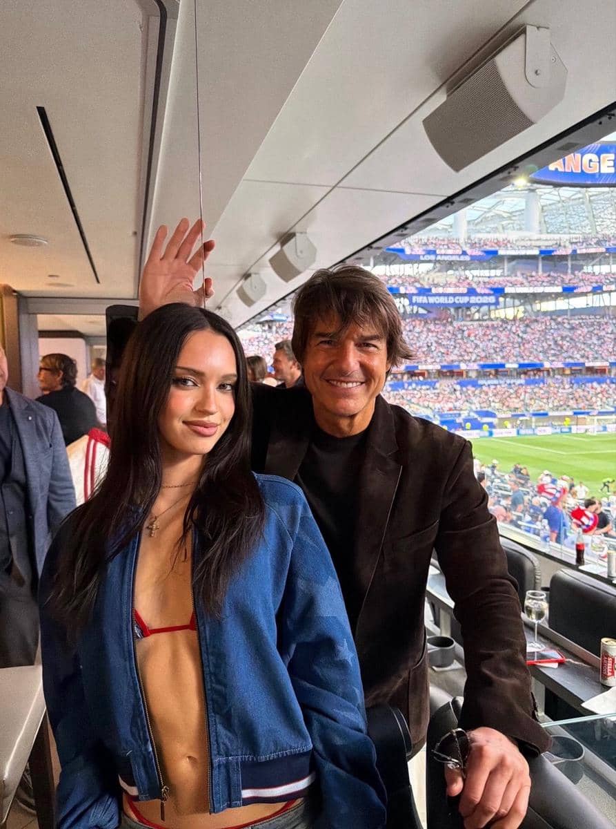 Dua orang berpose di area VIP stadion saat menyaksikan pertandingan Piala Dunia 2026 dengan latar tribun penonton yang penuh.