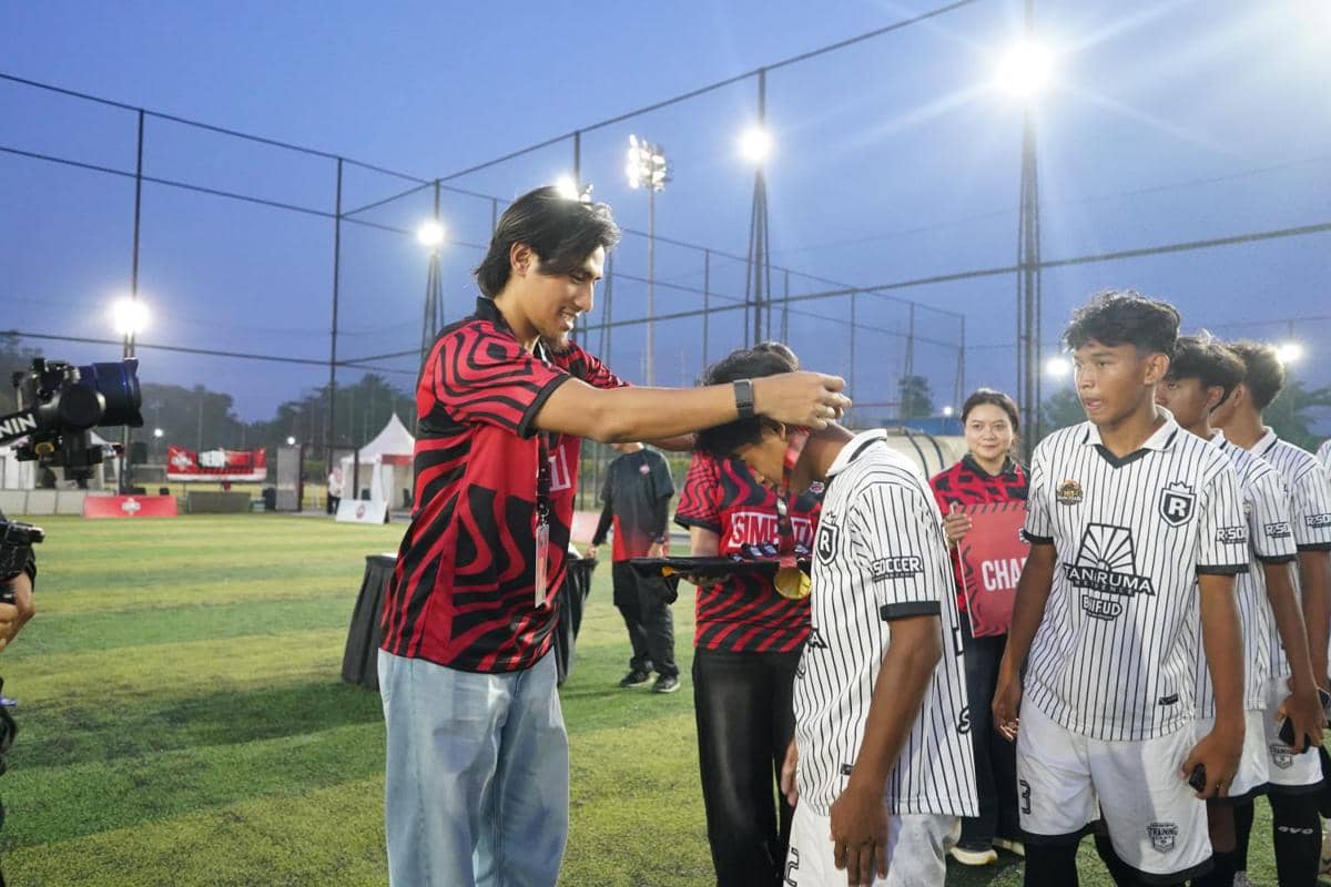 Seorang panitia mengenakan medali kepada pemain muda dalam acara penutupan Future Star Competition di lapangan sepak bola.