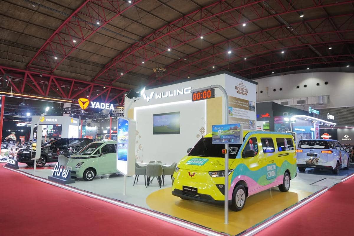 Stan pameran Wuling menampilkan dua mobil listrik berwarna cerah di ajang otomotif dalam ruangan dengan pencahayaan modern.