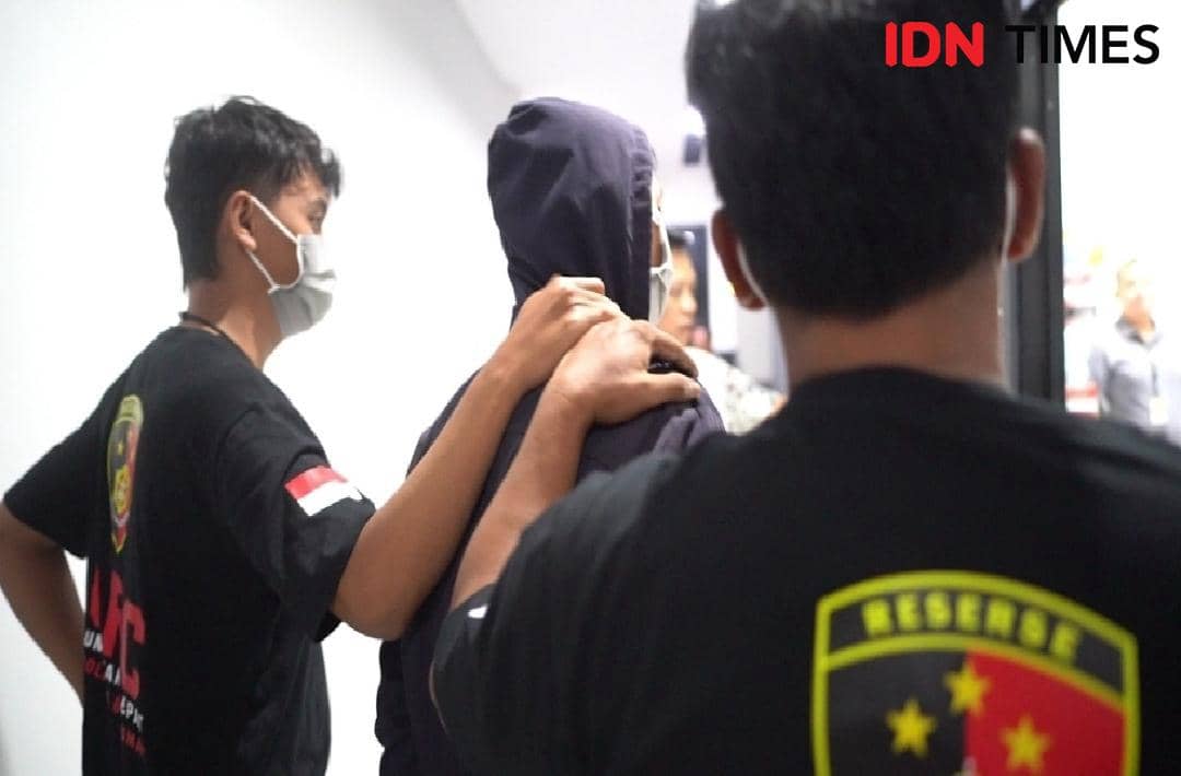 Petugas kepolisian menggiring seorang pria berjaket hitam dengan tudung kepala ke ruang pemeriksaan di Polresta Banyumas.