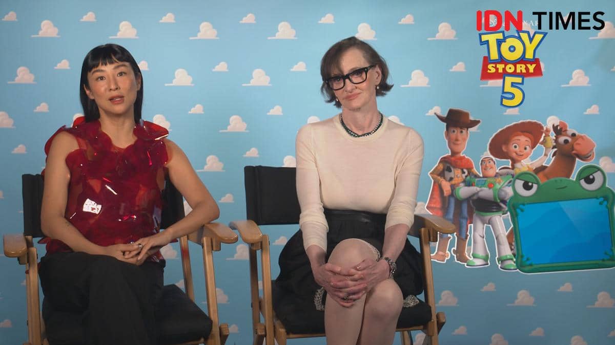 Dua pengisi suara duduk di kursi wawancara virtual dengan latar promosi film animasi Toy Story 5 bergambar karakter Woody dan Buzz Lightyear.