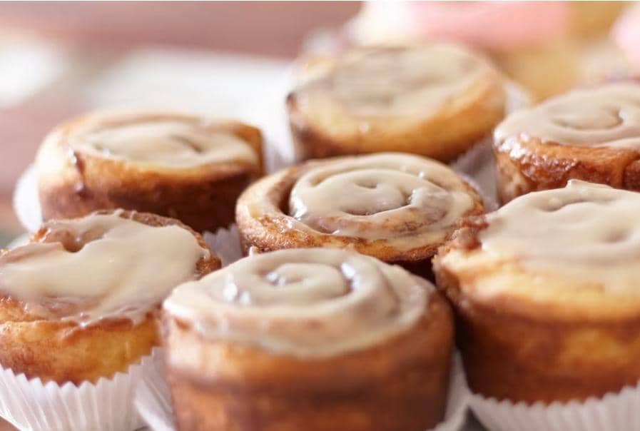 Ilustrasi cinnamon bun bites, potongan roti gulung kayu manis berlapis gula dan disajikan di atas piring.