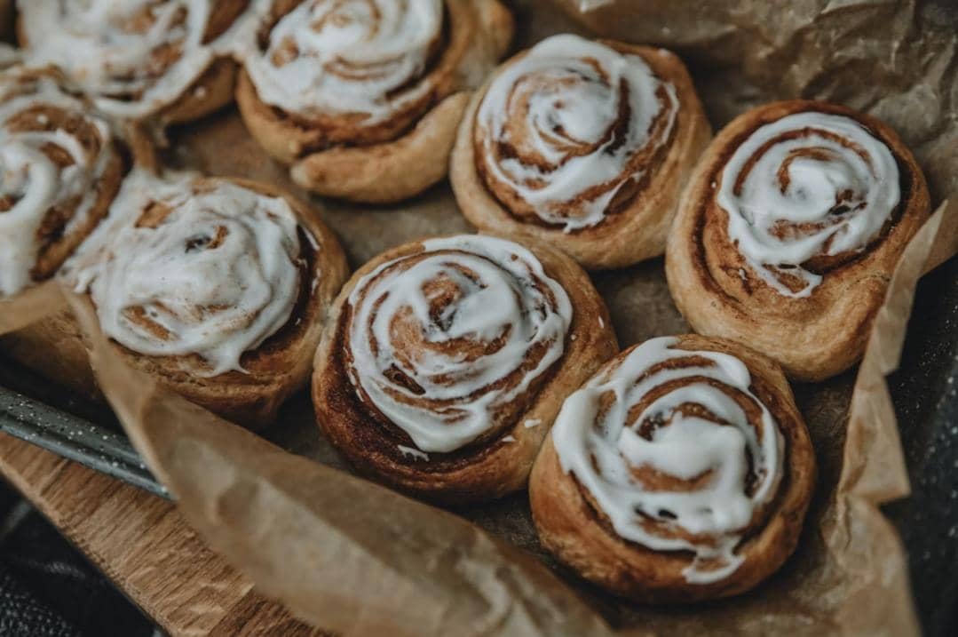 Ilustrasi cinnamon bun bites berukuran kecil dengan lapisan gula dan kayu manis, disajikan sebagai camilan manis.
