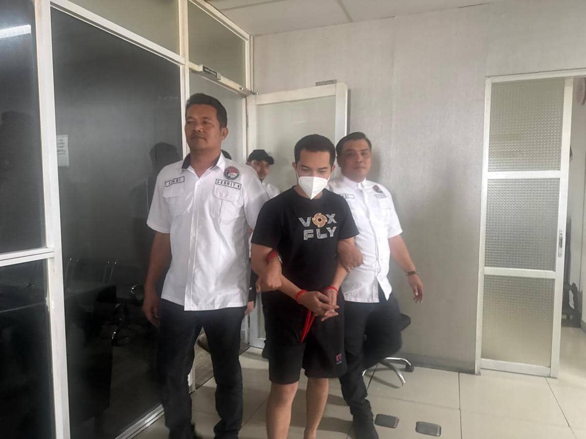 Petugas kepolisian mengawal seorang pria yang diborgol dan mengenakan masker di dalam gedung Bandara Soekarno-Hatta.