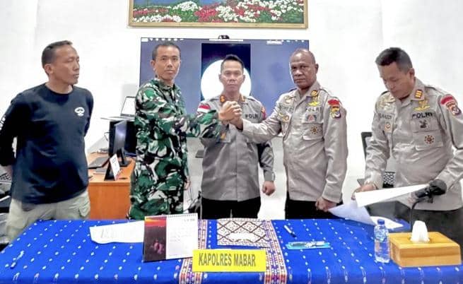 Pejabat Brimob dan anggota Kodim 1630 Manggarai Barat berjabat tangan di meja bertaplak biru dalam pertemuan perdamaian di Labuan Bajo.