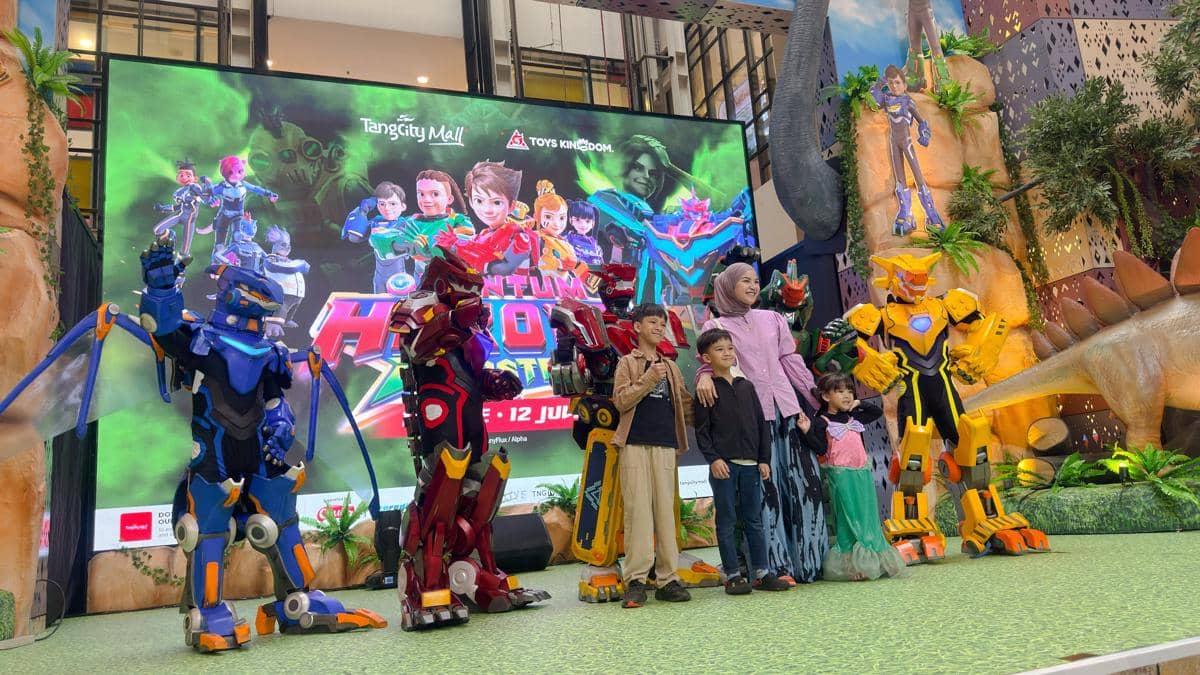Seorang ibu bersama tiga anak berpose dengan karakter robot warna-warni di acara liburan sekolah di TangCity Mall, Tangerang.
