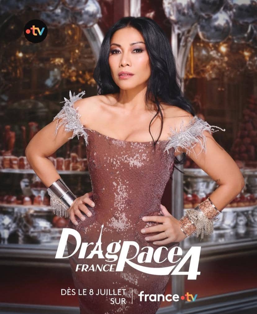 Seorang wanita bergaun cokelat berkilau berpose percaya diri di depan latar dekoratif dengan logo Drag Race France musim keempat.