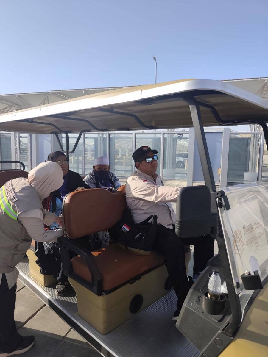 Petugas membantu penumpang menaiki golf car di Bandara Prince Mohammad bin Abdulaziz, Madinah, di bawah langit cerah.
