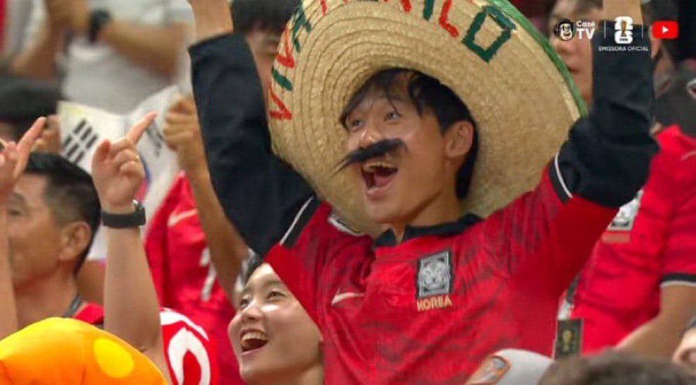 Seorang penonton mengenakan kostum lucu dengan topi sombrero besar dan kumis palsu saat mendukung tim Korea di Piala Dunia 2026.
