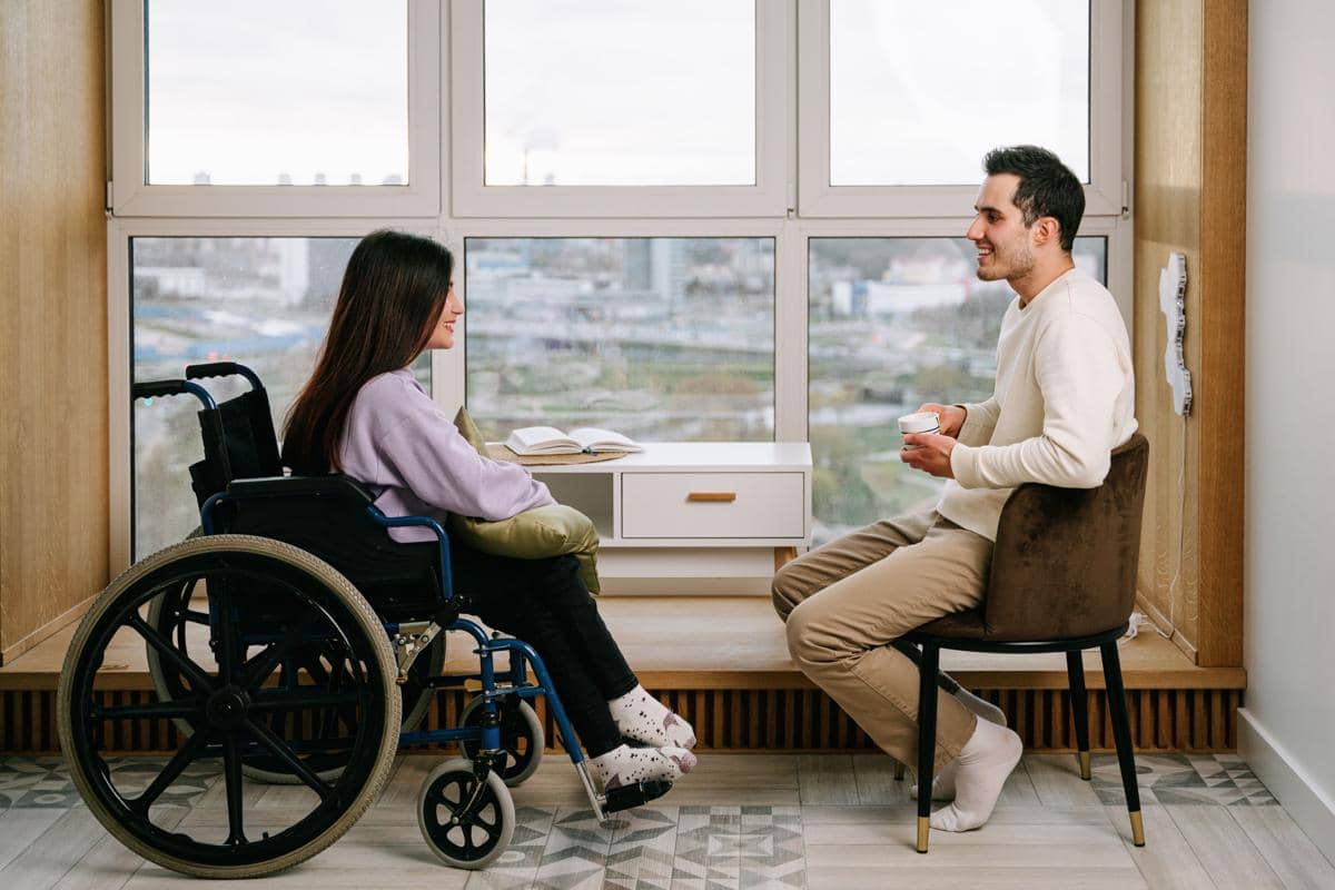 Seorang pria mengobrol dengan seorang wanita penyandang disabilitas.