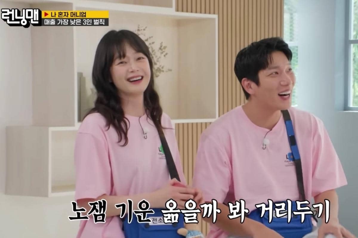 Dua peserta Running Man mengenakan kaus pink tersenyum ceria saat syuting episode 806 di dalam ruangan dengan latar kayu terang.