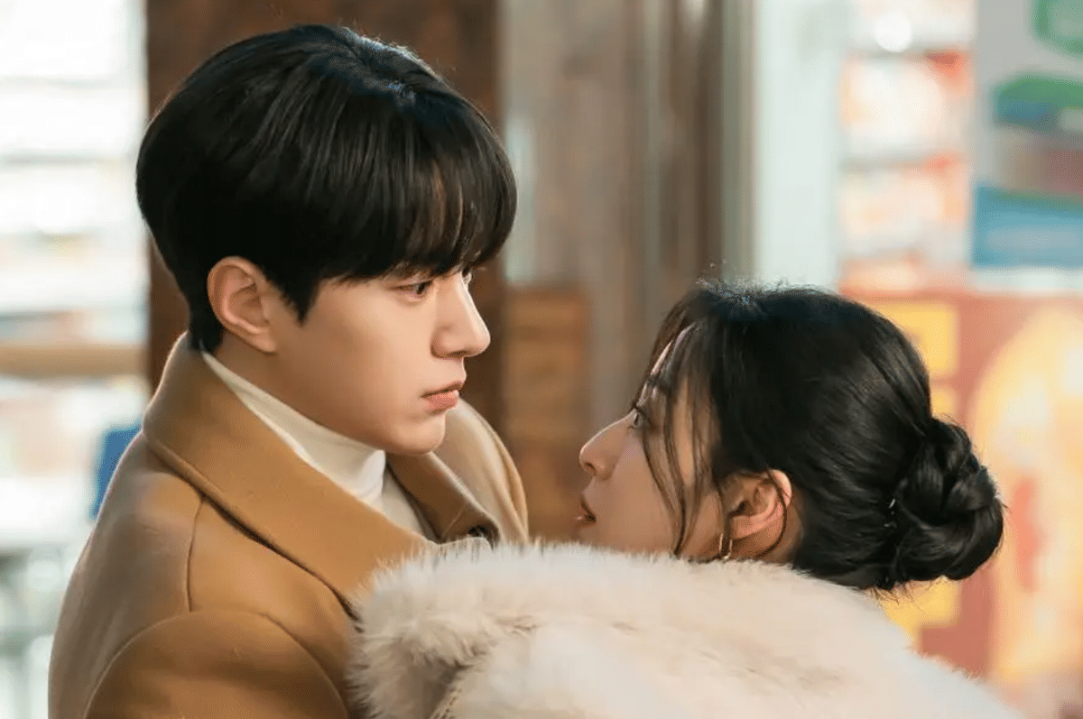 Dua karakter utama dalam drama Love In Sync saling menatap dekat di suasana musim dingin dengan pakaian hangat berwarna cokelat dan putih.