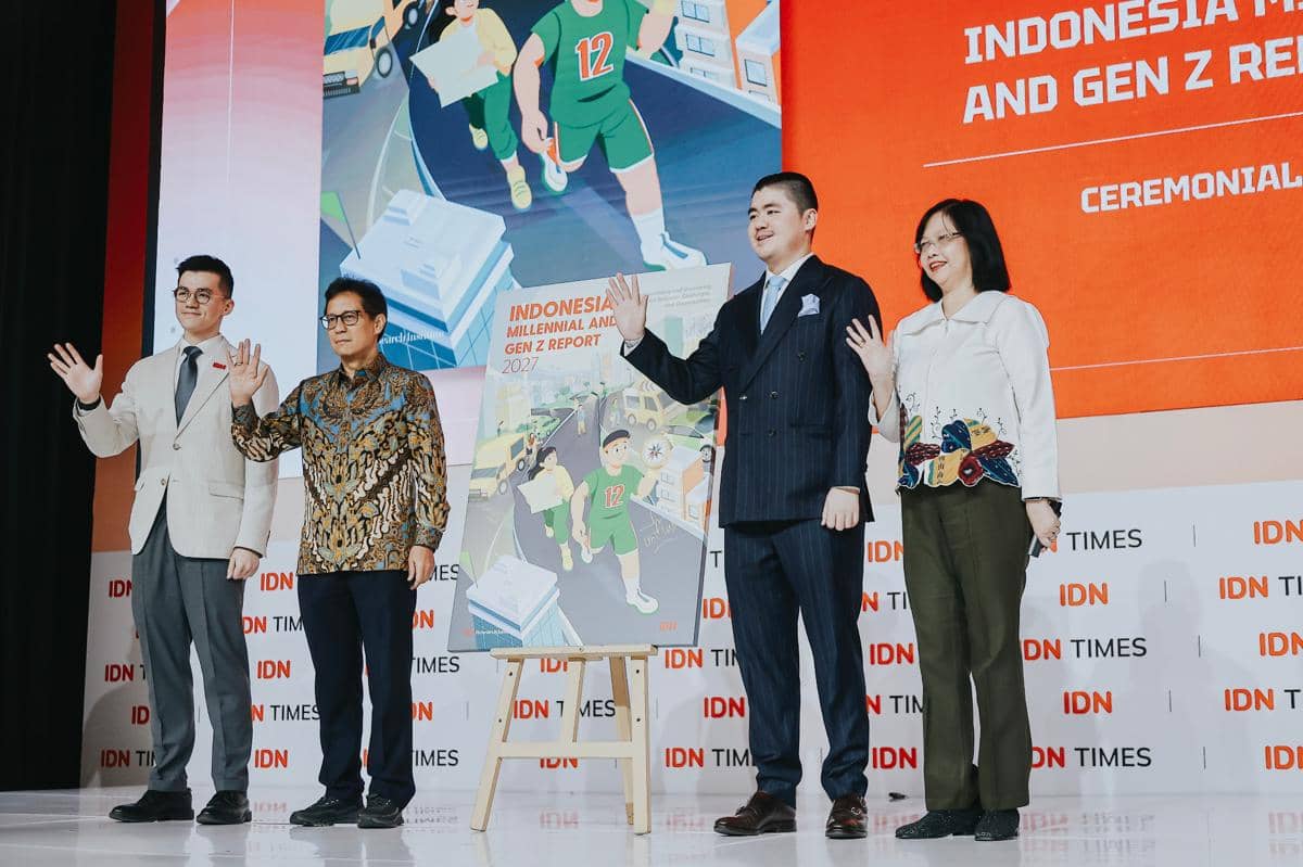 Empat orang berdiri di atas panggung saat seremoni penandatanganan Indonesia Millennial & Gen Z Report 2027 dengan latar spanduk IDN Times.