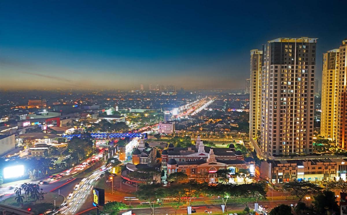Pemandangan malam kawasan Gading Serpong dengan gedung tinggi, jalan raya yang ramai, dan lampu kota yang berkilauan.